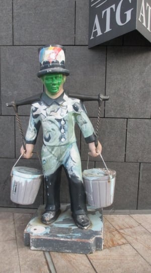 male in green and black collared long sleeve shirt carrying 2 bucket ceramic figurine thumbnail