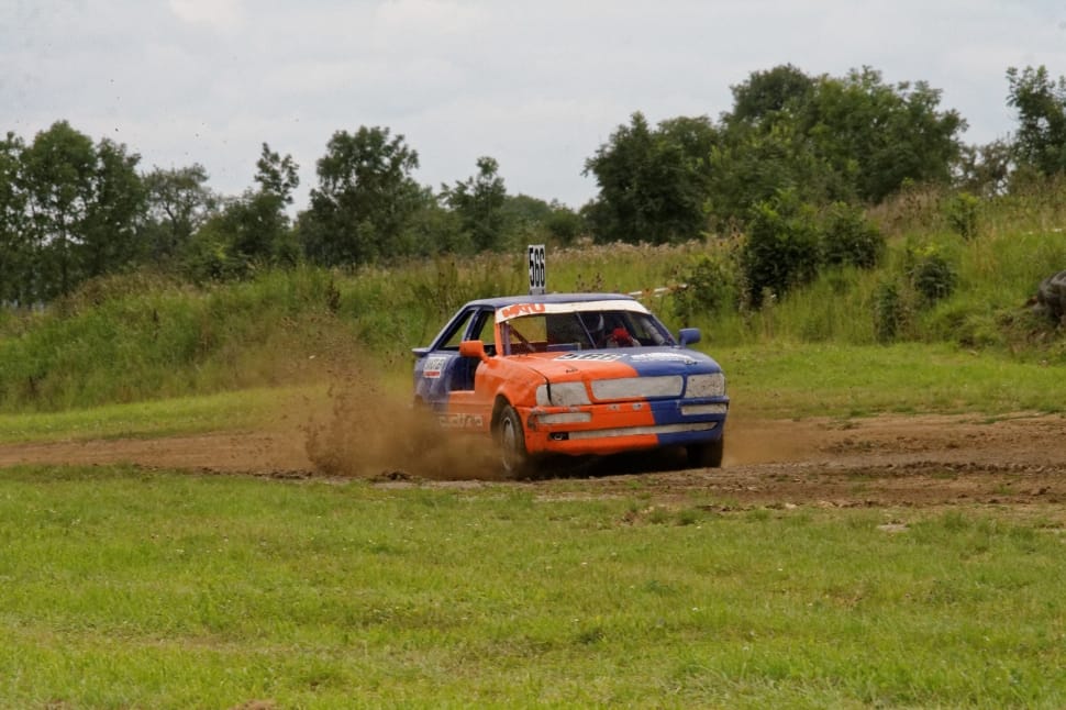 blue and orange racing car on dirt road during daytime preview
