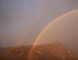 rainbow on brown mountain range thumbnail