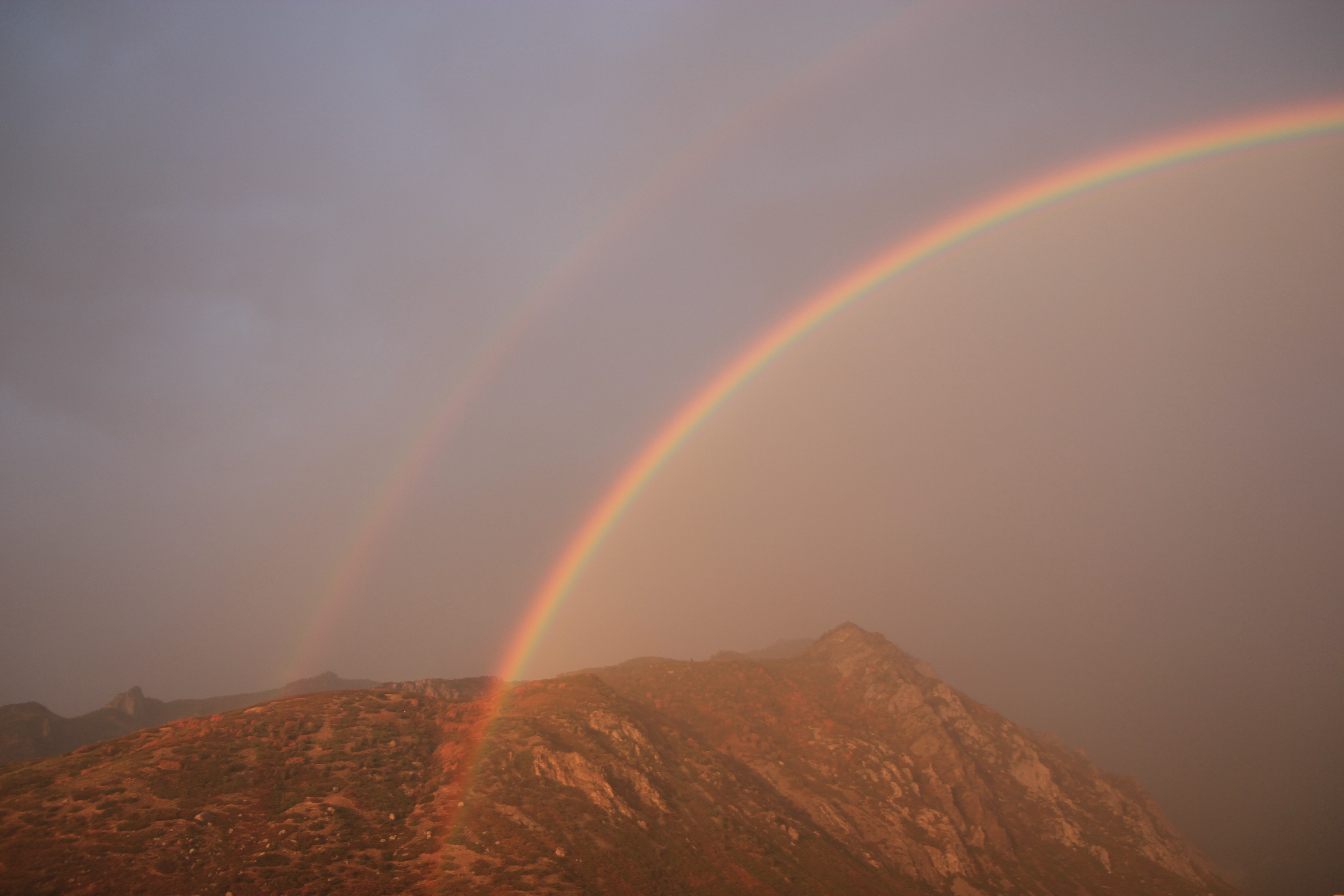 rainbow on brown mountain range
