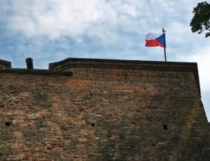 orange and brown concrete bricks wall with flag raised on daytime thumbnail
